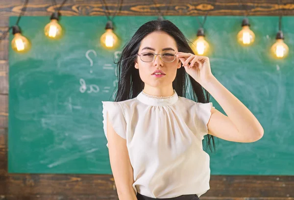 Vrouw met lange haren in witte blouse staat in de klas. Strenge leraar concept. De strenge leraar Lady op kalme gezicht staat voor schoolbord. Sexy wens leraar in de buurt van schoolbord met wiskunde heeft — Stockfoto