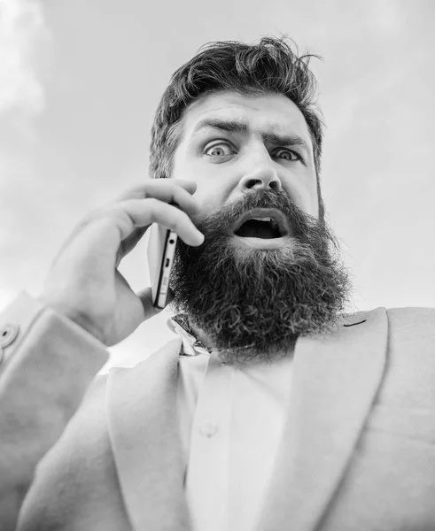 Man bearded surprised businessman hold mobile phone sky background. Hipster smartphone call partner. Man mobile call smartphone. Stay in touch. Mobile call concept. Important mobile conversation