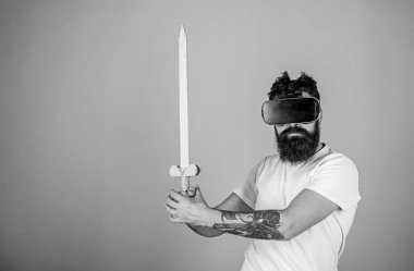 Oyun kavramı. Vr gözlük, açık mavi renkli sakallı adam. Hipster ciddi bir yüz üzerinde sanal gerçeklik oyun oyun keyfini çıkarın. Adam kafa monte ekran ile kılıç, oyun Vr oyunda mücadele tutar.