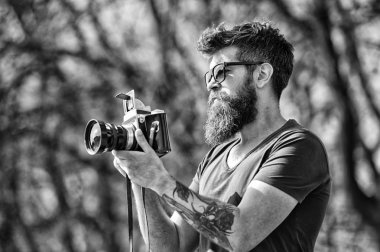 Fotoğrafçı sakal ve bıyık amatör fotoğrafçı doğa arka plan ile. Fotoğraf çekimi ile meşgul uzun sakallı adam. Fotoğrafçı kavramı. Adam sakallı hippi fotoğrafçı tutun vintage fotoğraf makinesi