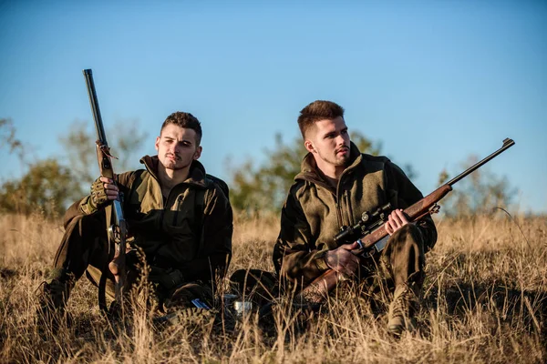 Hunters with rifles relaxing in nature environment. Hunting with friends hobby leisure. Hunters friends enjoy leisure. Hunters satisfied with catch drink warming beverage. Rest for real men concept.