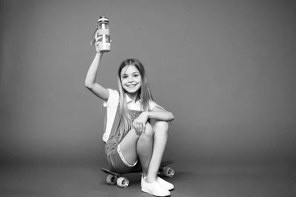 水和滞在します。女の子の幸せそうな顔を座っているペニー ボード紫背景中の水のボトルを保持します。子供女の子ケア体水分補給します。アクティブなレジャーと水のバランス。アクティブで健康的な子供は、水を飲む — ストック写真