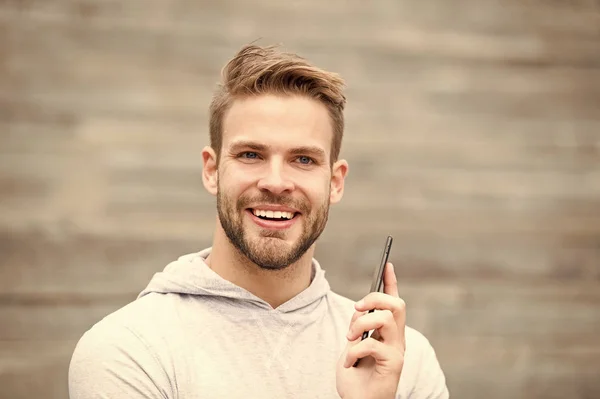 Hombre con barba camina con smartphone, fondo urbano con escaleras. El hombre con barba en la cara sonriente habla en el teléfono inteligente. Concepto de comunicación. Chico feliz de responder la llamada en el teléfono inteligente — Foto de Stock