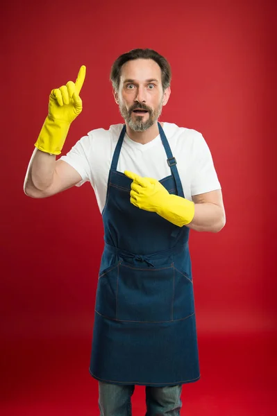 Just look over there. Mature man pointing finger up in yellow gloves. Mature household worker presenting something. Senior man wearing bib apron and rubber gloves. Providing household service — Stock Photo, Image