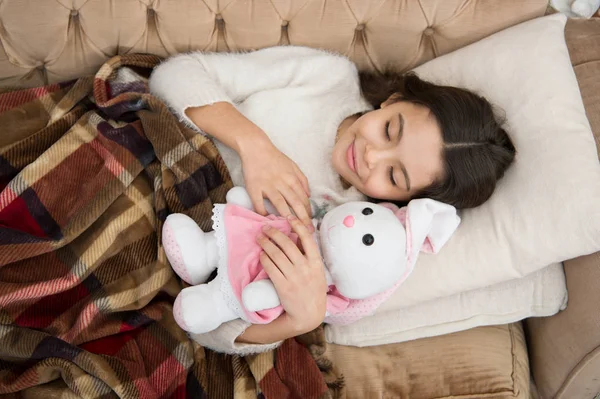 Play soft toy before go sleep. Sleep with toy. Girl enjoy evening time with favorite toy. Kid lay bed and hug bunny toy couch pillow blanket background top view. Girl child wear pajamas hug bunny — Stock Photo, Image