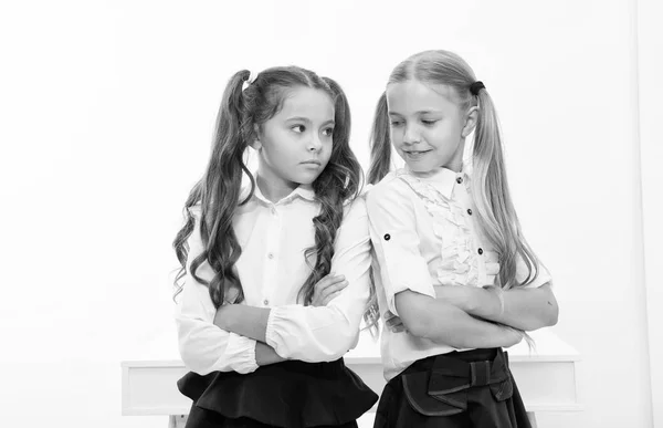 Små flickor i skoluniform hålla armarna korsade. Tillbaka till skolan och ser bra ut i nya skoluniform. små flickor. — Stockfoto