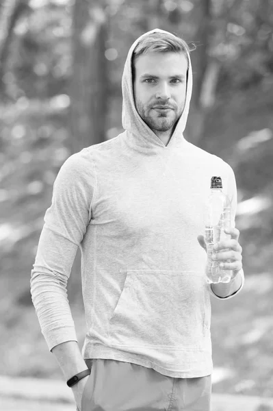 Refreshing vitamin drink after great workout. Man athletic appearance holds water bottle. Athlete drink water after training in park. Man athlete hold bottle care hydration body after workout