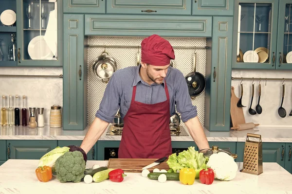 Lebensmittel mit gesunden Vitaminen auf dem Tisch und Mann mit Kochmütze in der Küche. Essenszubereitung und Kochrezepte — Stockfoto