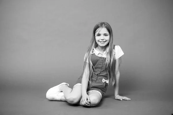 Conta-me a tua história. Menina cara feliz sentar no chão pronto ouvir história fundo violeta. Menina miúdo com cabelo longo roupa bonito relaxar esperar história interessante. A criança está na moda. Conceito de tempo de história — Fotografia de Stock