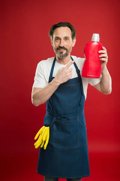 På vakt av renlighet och ordning. Städning och hushåll plikt. Man i förkläde med handskar håller plastflaska flytande tvål kemiska rengöringsmedel. Städning dag idag. Skäggig kille rengöring hem — Stockfoto