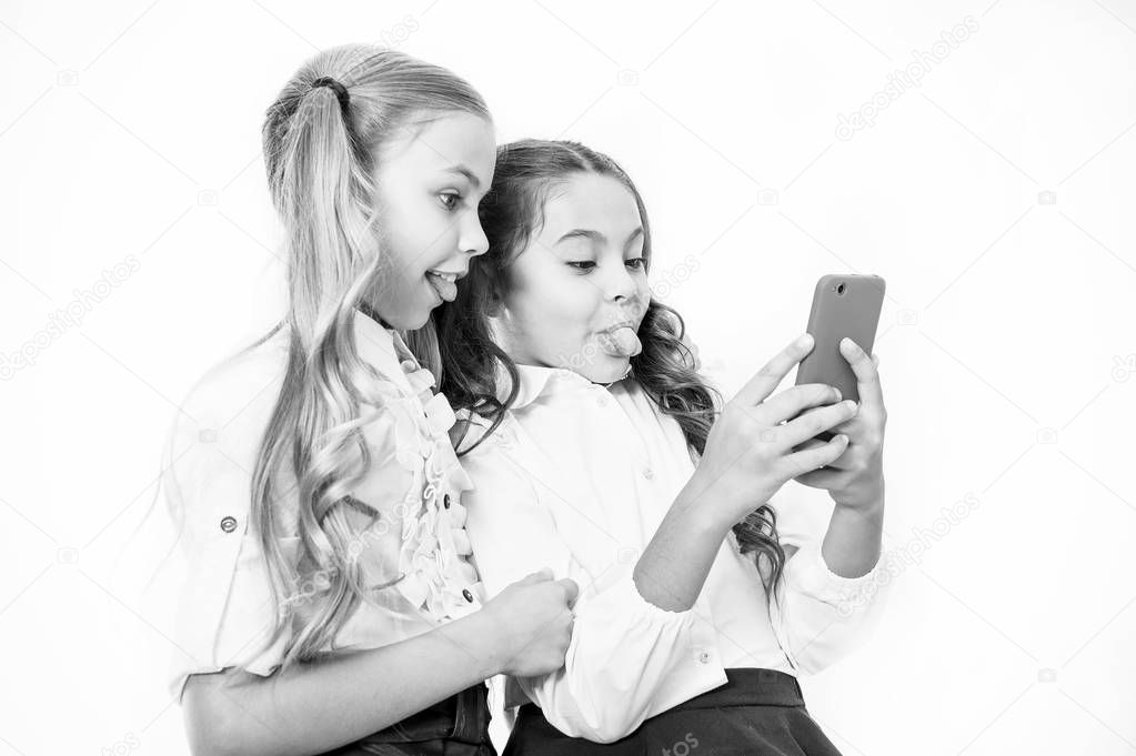 Online entertainment concept. Schoolgirls use smartphone check social networks. Send message friend. Online communication. Send selfie social network. Grimace for funny selfie. Posting funny photos