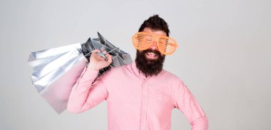 Alışveriş bağımlısı tüketici. Toplam satış konsepti. Adam çok alışveriş torbaları ile sakallı hippi. İndirim karşı koyamadım. Üstünde siyah Cuma alışveriş. Mutlu grup kağıt torbalar ile alışveriş. Karlı bir anlaşma