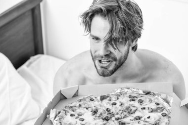 Evde yatakta lezzetli bir pizza yemek parlak bir apartman dairesinde öğrencidir. Ara diyet kavramı. Adam, kahvaltıda pizza seviyor. Yatak pizza.