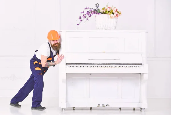重いピアノを移動しながら顔をしかめの発動機。疲れた男は白い背景に分離されたアパートのものを移転します。ホーム改装コンセプト — ストック写真