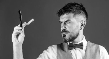 İpuçları bakım Kuaför sakal. Erkek yelek papyon ile usturanın mavi arka plan tutun. Kuaför sanat kavramı. Kuaför keskin tehlike ustura ile tıraşsız hippi. Berber Kuaför Salonu