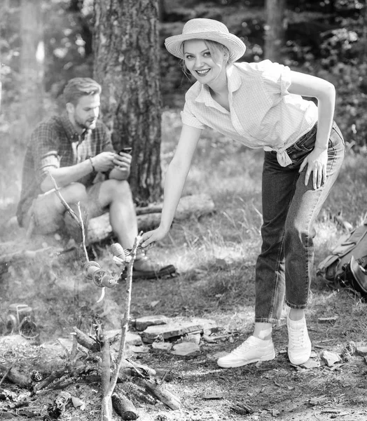 Fille en chapeau de paille cuisine des aliments au fond de la nature feu de camp. Conseils que chaque campeur doit savoir sur la cuisson des feux de camp. Conseils de camping. Conseils faciles pour améliorer votre cuisson au feu de camp. Aliments à cuire sur bâton — Photo