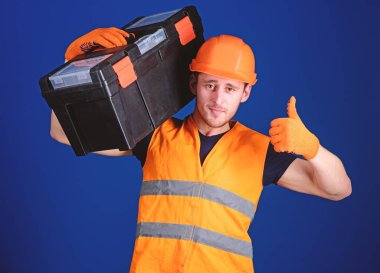 Kask, kask içinde adam araç kutusu tutar ve yukarı hareketi, mavi arka plan gösterir. Onarım istişare kavramı. İşçi, repairer, tamirci, emin yüz taşıyan araç omuz üzerinde Oluşturucu