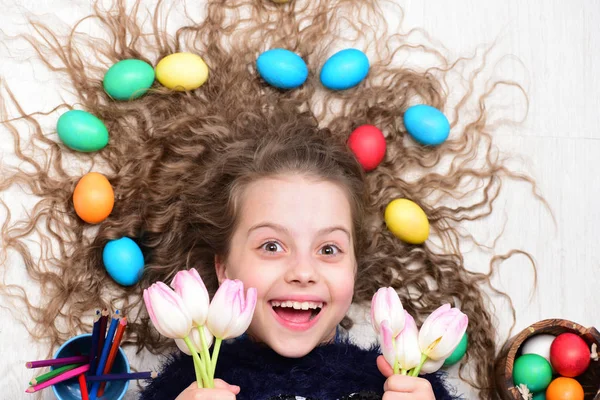 Fröhliches Ostermädchen, bunte Eier im langen Haar, Tulpenblumen — Stockfoto