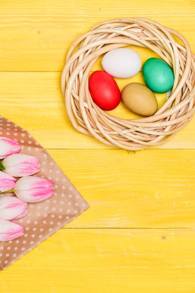 Bahar tatili. Mutlu Paskalya sezon. Paskalya yuvası. Paskalya yumurtası toplama. Bahar vibes. Renkli yumurta ve buket taze Lale çiçek sarı arka plan üzerinde görünümü top. Gelenek kutlamak Paskalya — Stok fotoğraf