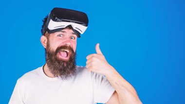 Mutlu yüz başparmak gösterilmesini uzun sakallı adam. Sakallı adam heyecanlı bakışla Vr kulaklık, dijital ilerleme kavramı, yeni modeli sınama. Üzerinde mavi arka plan izole trendy sakallı hippi