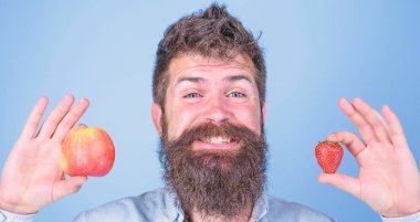Yaz aylarında faydaları. Sakallı adam gülen elma ve çilek eller mavi arka planda tutar. Vitamini meyve beslenme kavramı. Vitamini diyet sağlık. Meyve ve meyve eller sağlıklı alternatif
