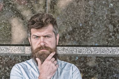 Sakal ve bıyık konsantre yüzünde siyah mermer zemin üzerine olan adam. Erkeklik kavramı. Tousled saçlı hippi sakal kameraya bakarken dokunur. Baktılar ve meraklı adam görünüyor