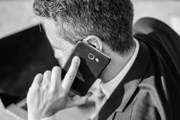 Call technical support service. Businessman holds smartphone near ear close up. Man formal suit call support while works with laptop rear view. Consultation and help concept. How can I help you — Stock Photo, Image