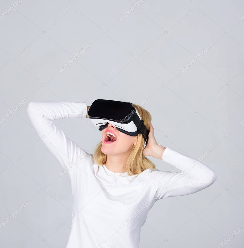 Amazed young woman touching the air during the VR experience. Portrait of young woman wearing VR goggles, experiencing virtual reality using 3d headset. Funny young woman with VR