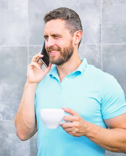 Man drink cappuccino speak phone grey wall background. Coffee can be endlessly reimagined make something old new again like entrepreneurs craft and reinvent businesses. Pleasant coffee break at work