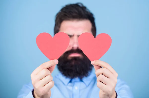 Happy in love. Love is amazing. Man bearded hipster with heart valentine card. Celebrate love. Guy attractive with beard and mustache in romantic mood. Feeling love. Dating and relations concept