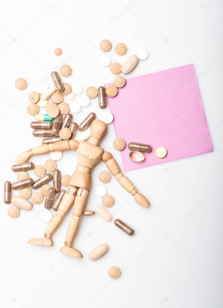 Health and treatment. Health care and problems. Immunity and medicine vitamins. Overdose and death. Medicine prescription. Wooden human dummy lay on pile of pills and tablets. Take medicine concept
