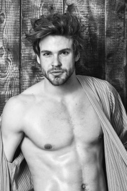 Adam parıldayan cilt soyunma bornoz. Seksi çekici maço tousled saç ahşap arka plan üzerinde. Adam atlet Sığdır gövde ile. Sporcu altı paketi seksi gövde göster. Bekarlığa veda seksi vücut göğüs ve karın