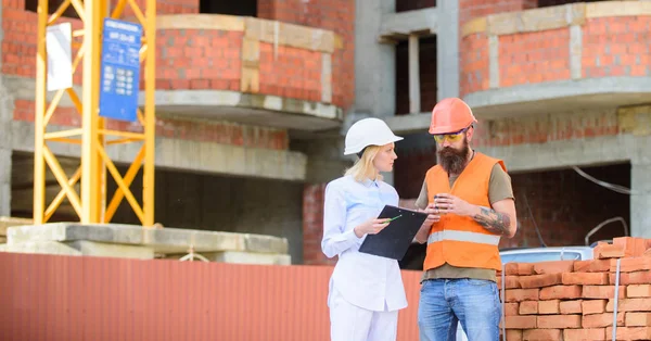 Concept de communication de l'équipe de construction. Relations entre les clients de la construction et les participants du secteur de la construction. Femme ingénieur et constructeur communiquent sur le chantier de construction. Discuter du plan — Photo