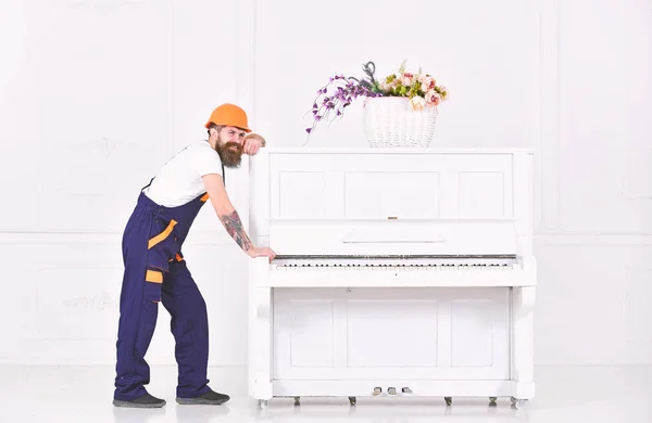 Obrero fuerte teniendo una rotura aislada sobre fondo blanco. Sonriente con bigote tratando de mover el piano blanco. Largo día en el trabajo — Foto de Stock