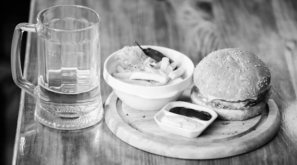 Hamburguesa con carne de queso y ensalada. Comida de bar y jarra de cerveza. Concepto de comida rápida. Menú de hamburguesas. Snack alto en calorías. Hamburguesa y papas fritas y salsa de tomate sobre tabla de madera. Deliciosa hamburguesa —  Fotos de Stock