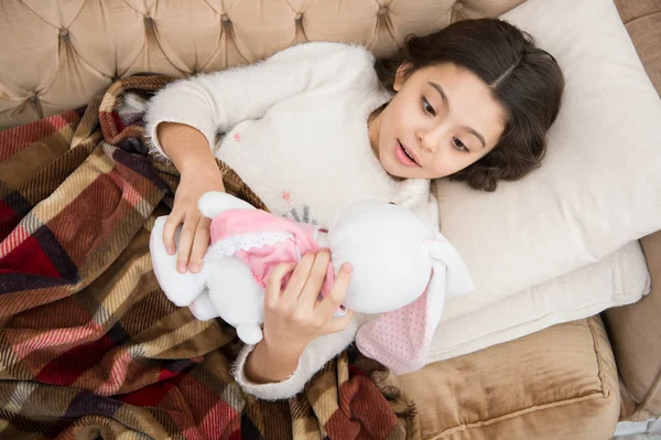 Kid laických postel a obejmout zajíček hračka gauč polštář Přikrývka pozadí pohled shora. Dívka dítě nosit pyžamo hug králíček. Hračka měkká před Jdi spát. Spát s hračkou. Dívka si večerní čas s oblíbenou hračkou — Stock fotografie