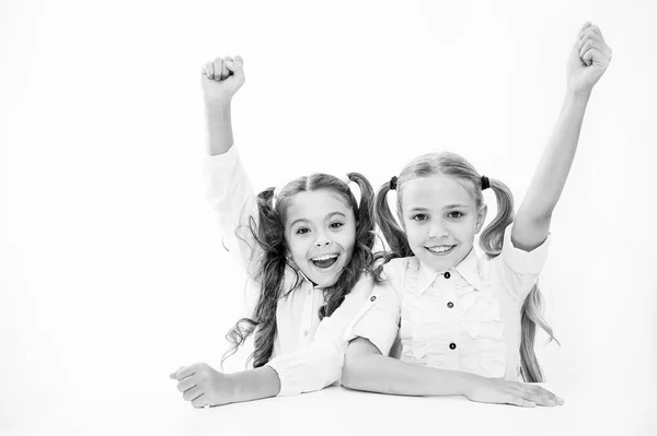 Las colegialas felices mantienen las manos en alto mientras se sientan en el escritorio fondo blanco. Gana el concurso de la escuela. Saben la respuesta correcta. Las colegialas emocionales alegres celebran la victoria. Equipo de ganadores. Trabajo en equipo y liderazgo —  Fotos de Stock