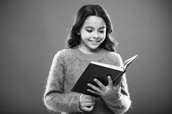 Attività di lettura per bambini. Ragazza tenere libro leggere storia su sfondo arancione. Bambino piace leggere il libro. Concetto di libreria. Meravigliosi libri gratuiti per bambini disponibili da leggere. Letteratura per bambini — Foto Stock