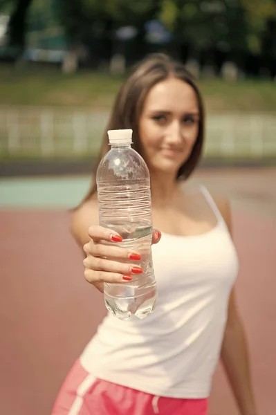Plastic bottle in hand with manicure. Water bottle in hand of blurred woman. Drinking water for health. Thirst and dehydration. Sport activity and energy