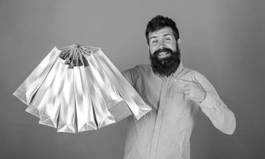 Sakal ve bıyık alışveriş torbaları, kırmızı arka plan işaret olan adam. Mutlu yüz hipster bağımlısı alışveriş veya Alışverişkoliğin. Satış sezon indirimlerle alışveriş adam. Alışveriş kavramı