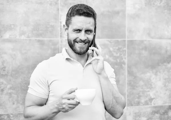 Man dricka cappuccino talar telefon grå vägg bakgrund. Skäl företagare dricker kaffe. Även om du dricker kaffe i farten är varje klunk liten paus i vardagen och lite ögonblick av egenvård — Stockfoto