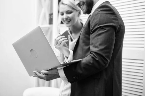 Job interview. Business and people concept. Two cheerful young people holding laptop and talking while standing in office.