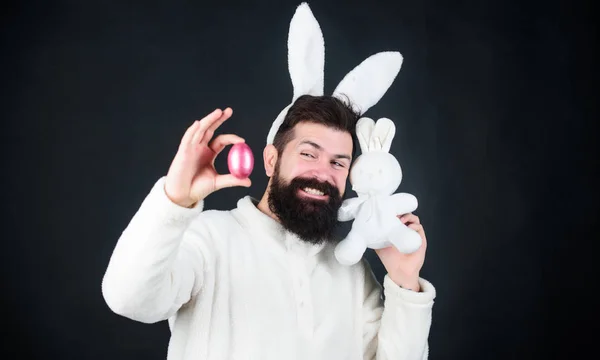 Весна, нове життя і родючість. Бородатий чоловік у костюмі кролика з пасхальним яйцем та іграшкою заєць. Весняне свято. Щасливий чоловік з кролячими вухами тримає іграшку та яйце. Нехай Великдень буде яєчним осередком — стокове фото