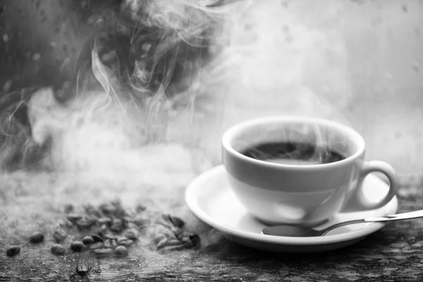 Coffee morning ritual. Fresh brewed coffee white mug and beans on windowsill. Wet glass window and cup of hot coffee. Autumn cloudy weather better with caffeine drink. Enjoying coffee on rainy day