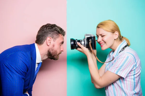 The power behind the picture. Businessman posing in front of female photographer. Pretty woman using professional camera. Photographer shooting male model in studio. Fashion shooting in photo studio