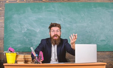 Öğretmen düşük bilgi seviyesini merak ediyordu. Sen neden bahsediyorsun? Hiç hoş değil. Ne aptalca bir düşünce. Erkek sakallı öğretmen ifadeyi merak ediyor. Sınıfın tahtasında oturuyor.