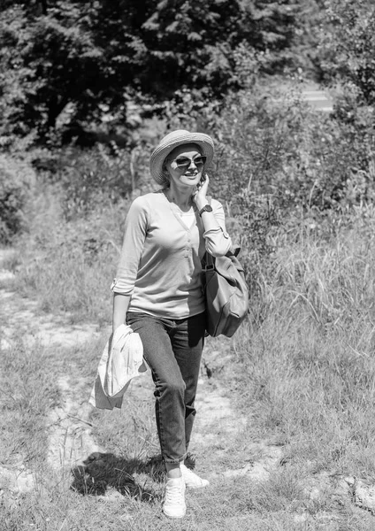 Woman going picnic in nature. Girl hiking or going to picnic in forest. Woman sunglasses carrying backpack. Pleasant walk in nature. Woman in straw hat walking in nature backgroun