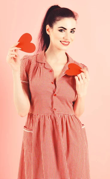 Ragazza attraente che tiene due cuori rossi tra le mani, isolati su sfondo rosa. Amore, felice, concetto di San Valentino — Foto Stock