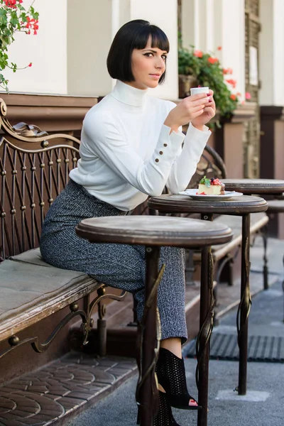 Tempo agradável e relaxamento. Lanche delicioso e gourmet. Menina relaxar café com café e sobremesa. Mulher atraente morena elegante desfrutar de sobremesa e café café terraço fundo. Conceito de sobremesa — Fotografia de Stock