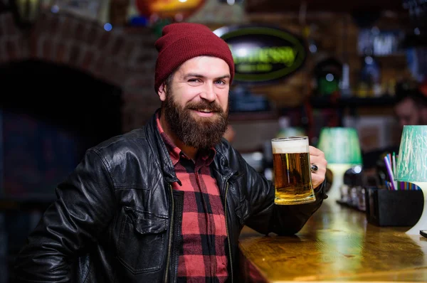 Guy bearded man sit at bar counter in pub. Weekend lifestyle. Pub great place to dine drink and have fun. Hipster relaxing at pub. Man with beard spend leisure in dark pub. Brutal hipster relaxing